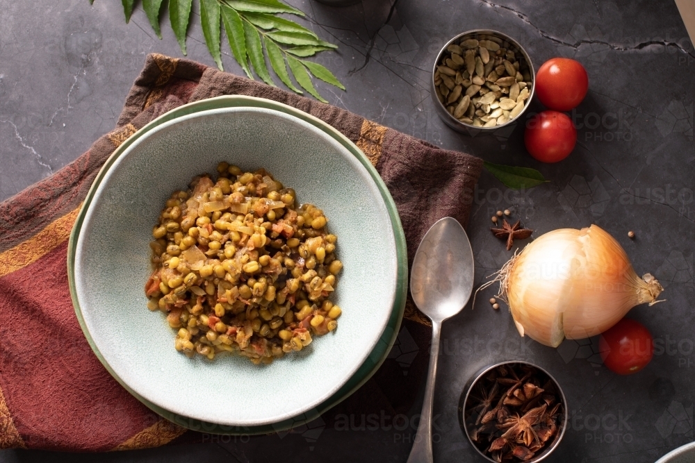 Bowl of Dahl Curry and ingredients around on dark background - Australian Stock Image