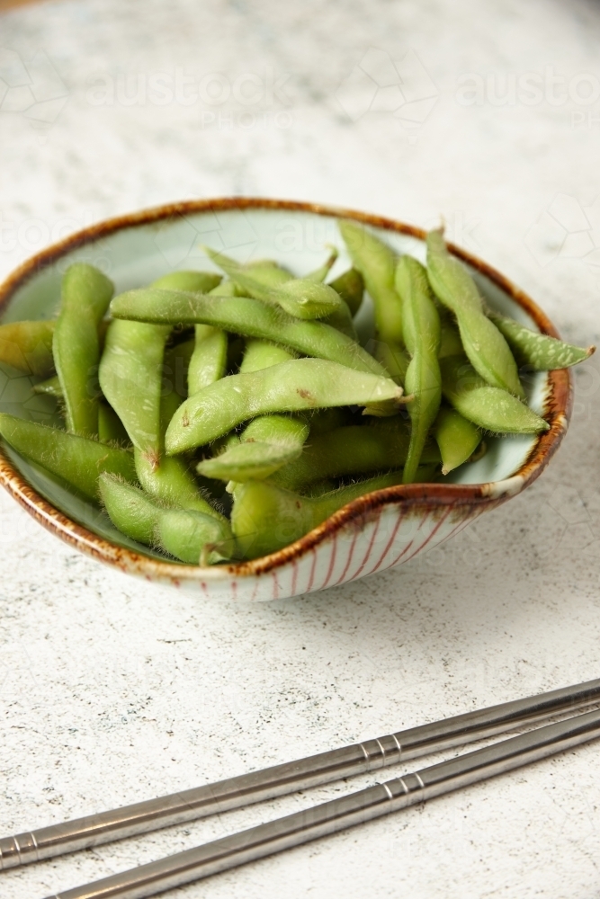 bowl of edamame with metal chopsticks - Australian Stock Image