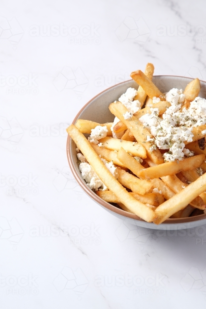 Bowl of hot chips with sprinkled feta cheese - Australian Stock Image