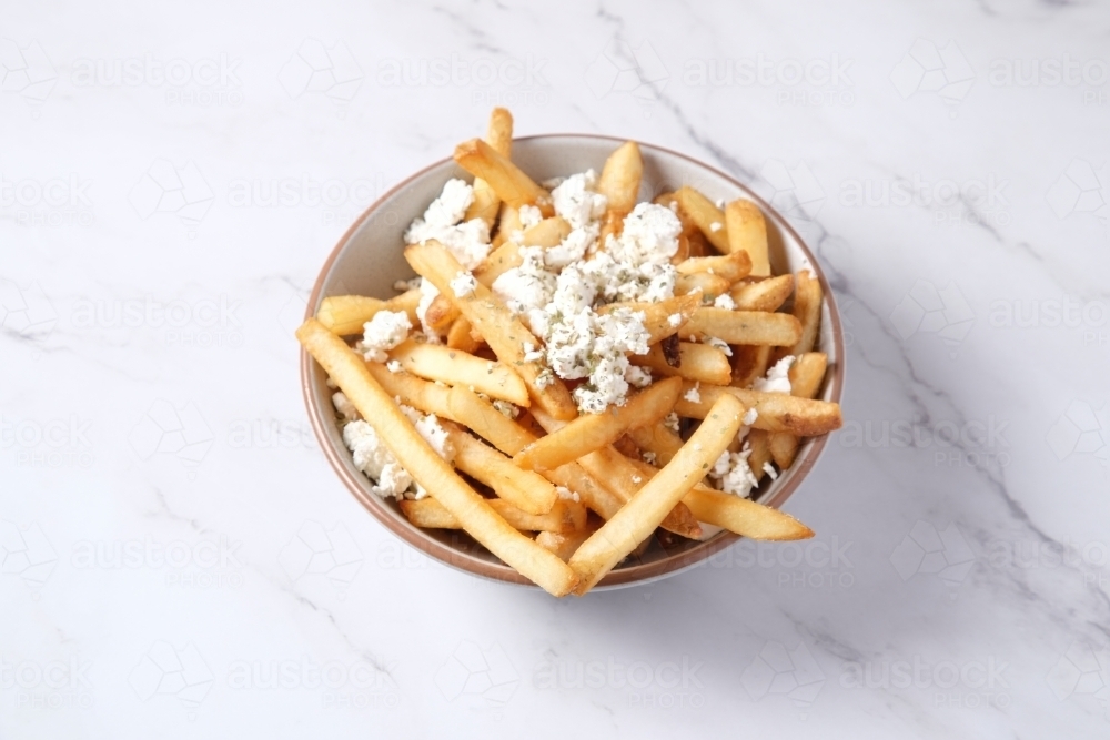 Bowl of hot chips with sprinkled feta cheese - Australian Stock Image