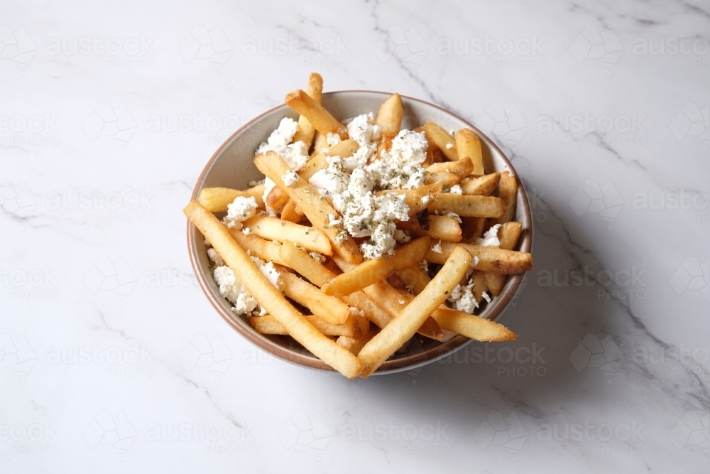 Bowl of hot chips with sprinkled feta cheese - Australian Stock Image