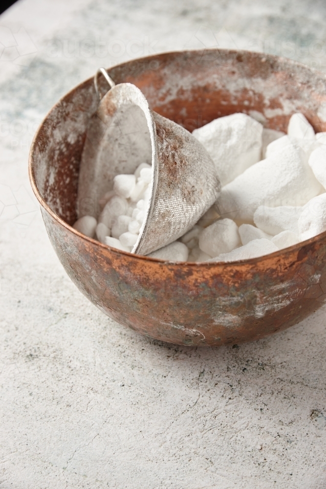 Bowl of lumpy icing sugar with sieve - Australian Stock Image