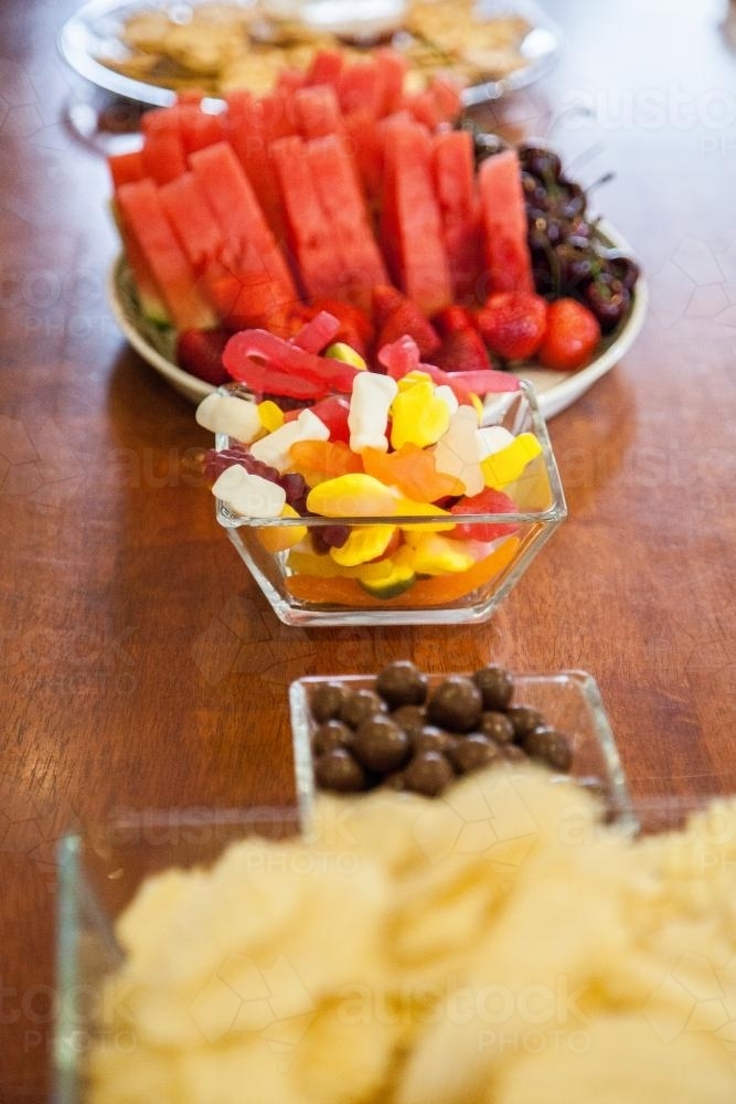 Bowls of lollies, fruit, chips and chocolate ready for a party - Australian Stock Image