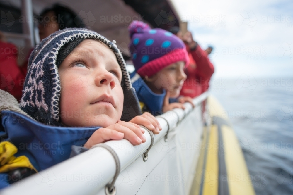 Boy and girl looking out of boat on a chilly cold day at ocean and sky - Australian Stock Image