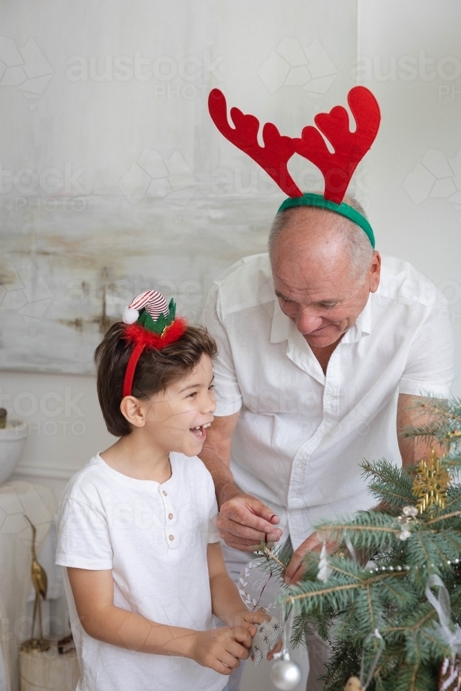 Boy and granddad decorating Christmas tree together - Australian Stock Image