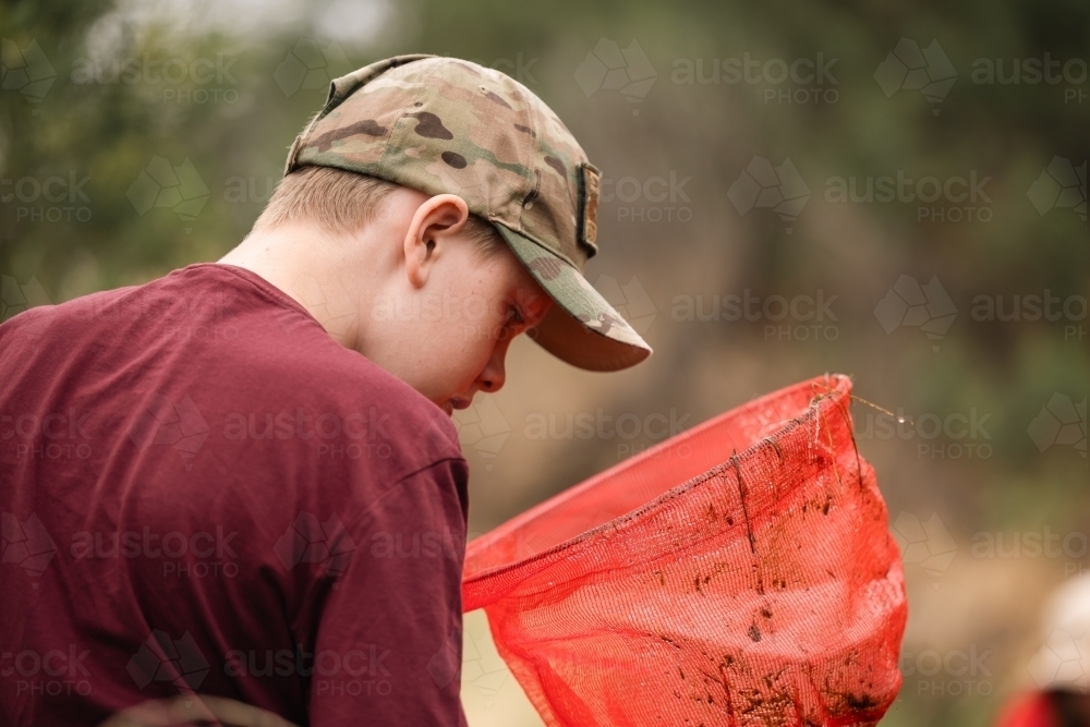 Boy catching tadpoles. Outdoor nature activity. - Australian Stock Image