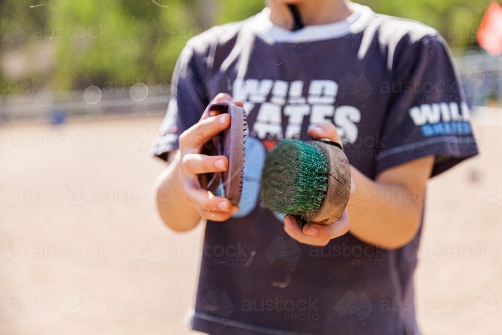 Boy cleaning brush with curry comb - Australian Stock Image