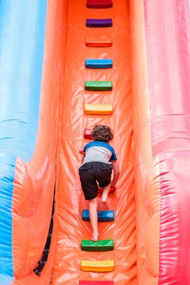 Boy climbing up ladder of blow up slide at local show - Australian Stock Image