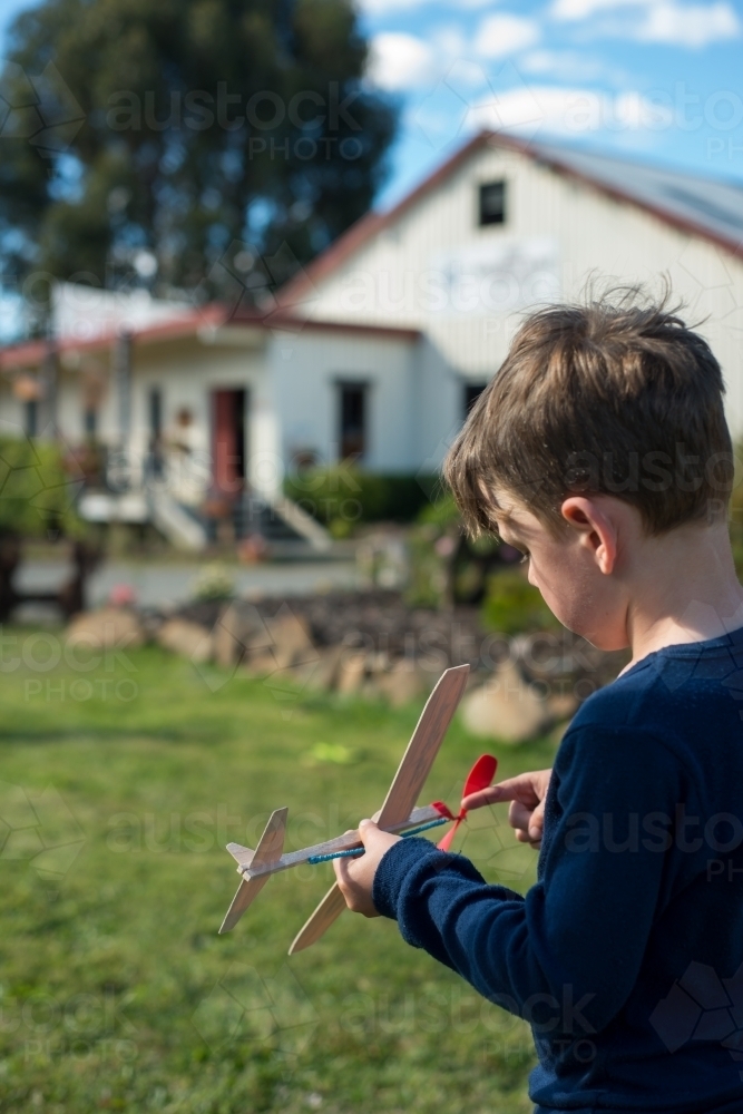 Boy flying plane with father on green grass - Australian Stock Image