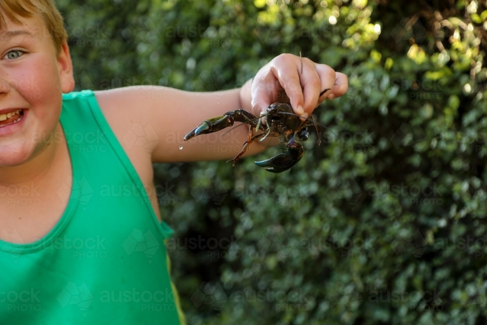 Boy holding yabby, summer in a country backyard - Australian Stock Image