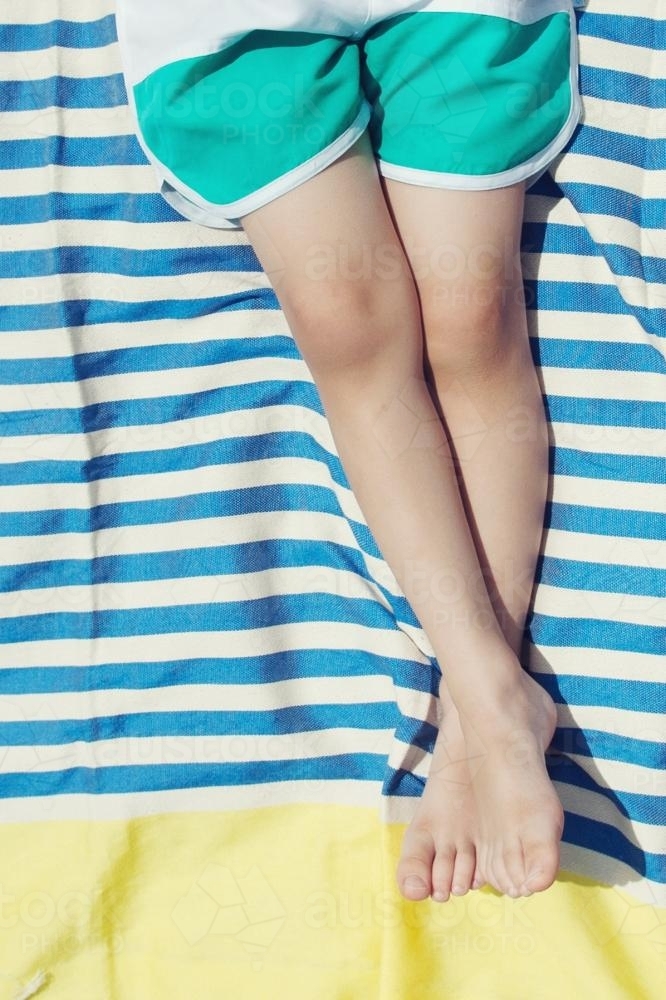 Boy laying on turkish towel sunbaking - Australian Stock Image