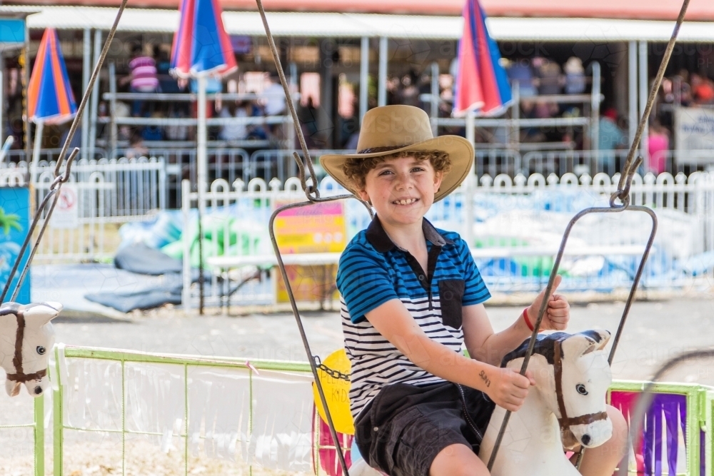 Boy on horse ride at local show wearing akubra hat smiling with thumbs up - Australian Stock Image