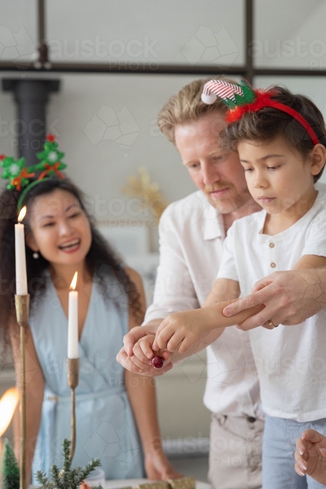 Boy placing cherry with help of parents - Australian Stock Image