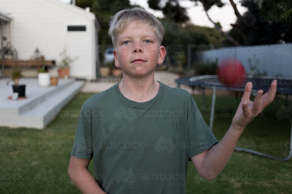 Boy playing backyard cricket at dusk - Australian Stock Image