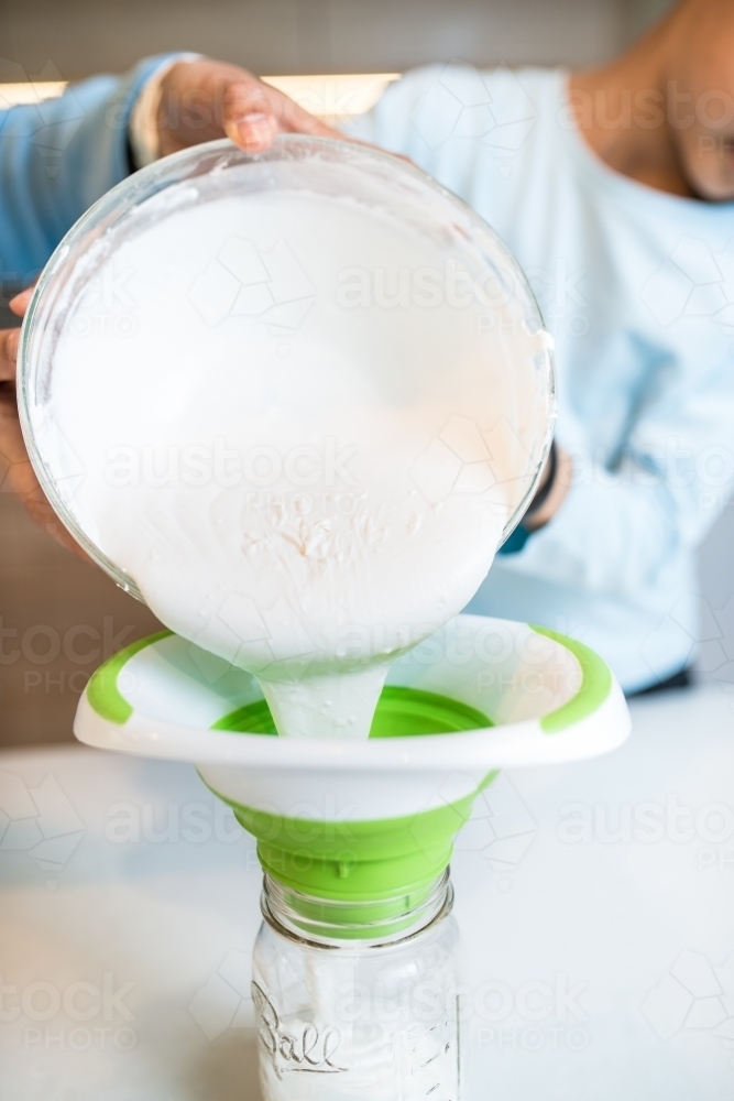 Boy pouring cream from bowl - Australian Stock Image