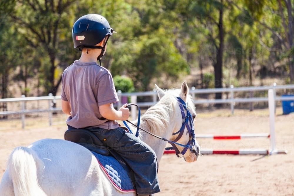 Boy riding horse away - Australian Stock Image