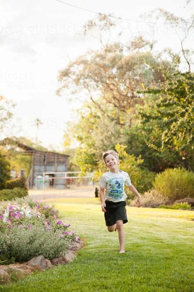 Boy running in backyard - Australian Stock Image