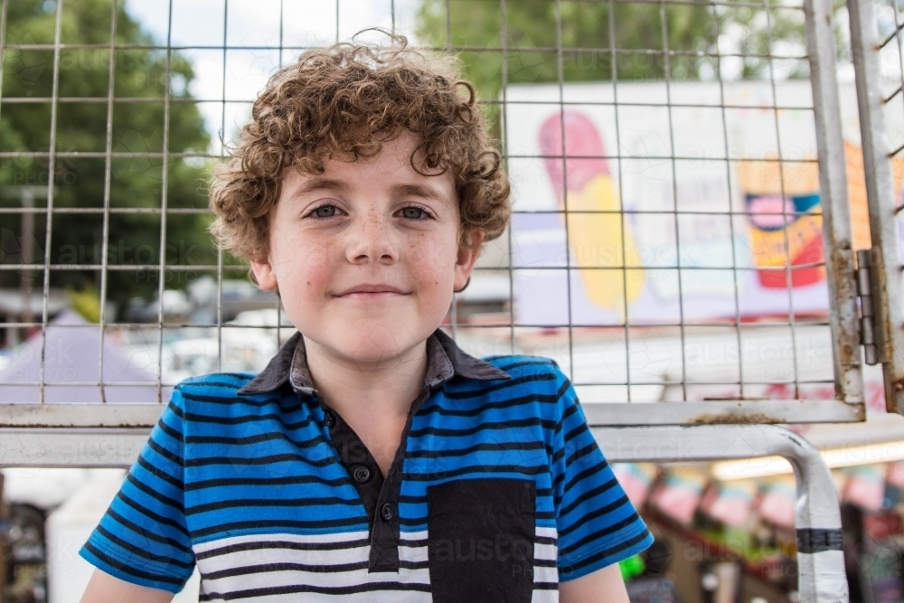 Boy sitting in ferris wheel cage at local show - Australian Stock Image