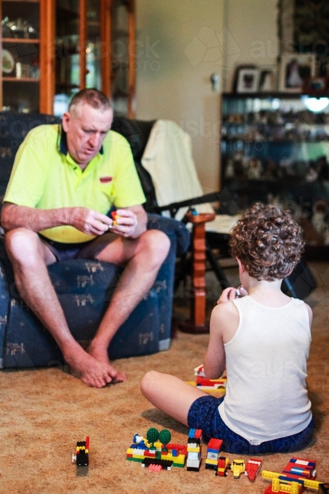 Boy sitting with grandfather playing with blocks together - Australian Stock Image