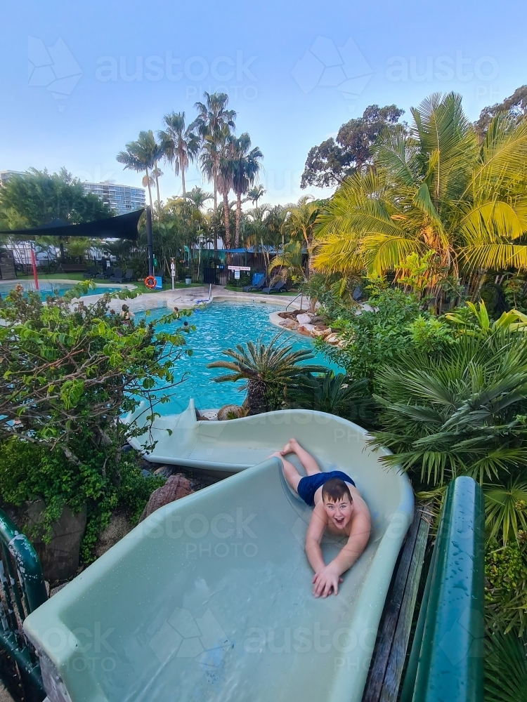 Image of Boy sliding backwards down water slide at caravan park ...