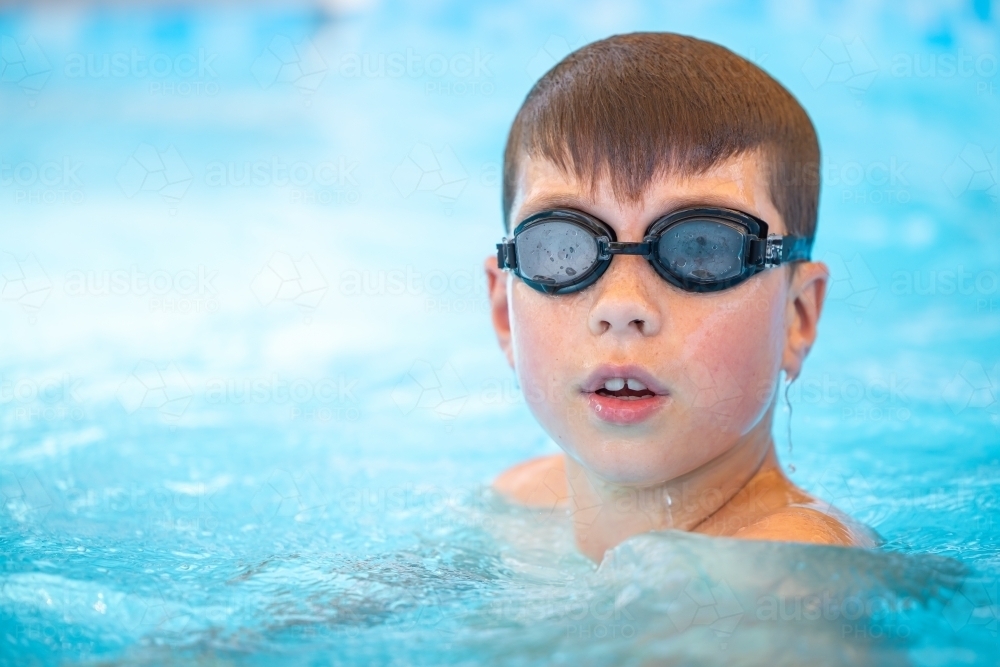 Boy swimming in pool wearing goggles - Australian Stock Image