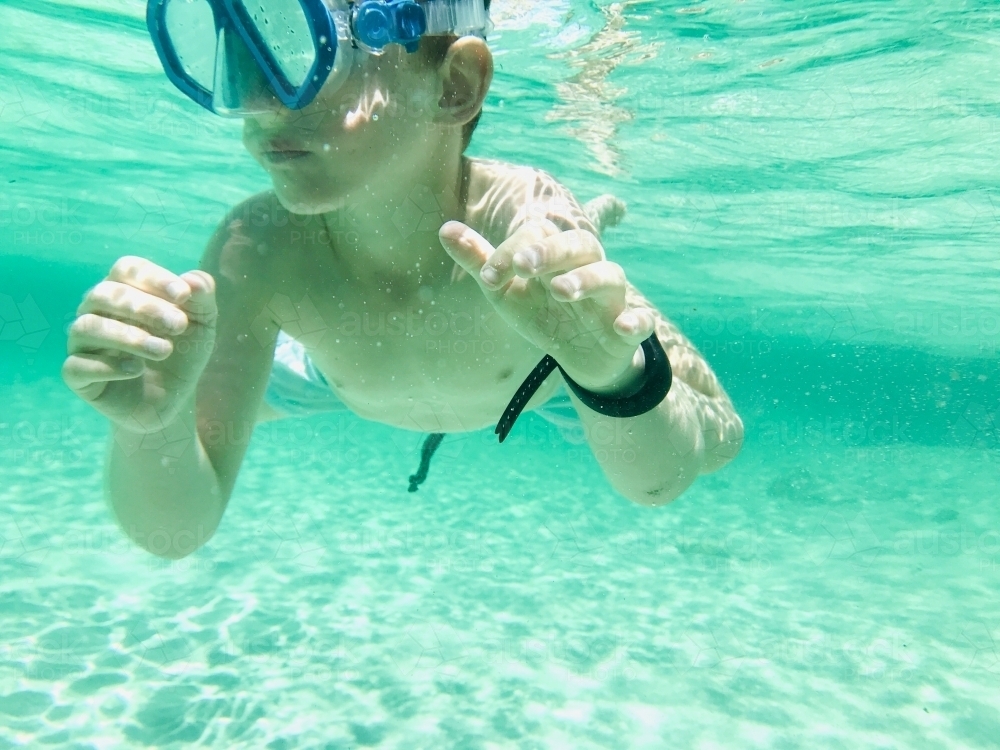 Boy swimming underwater wearing snorkel mask - Australian Stock Image