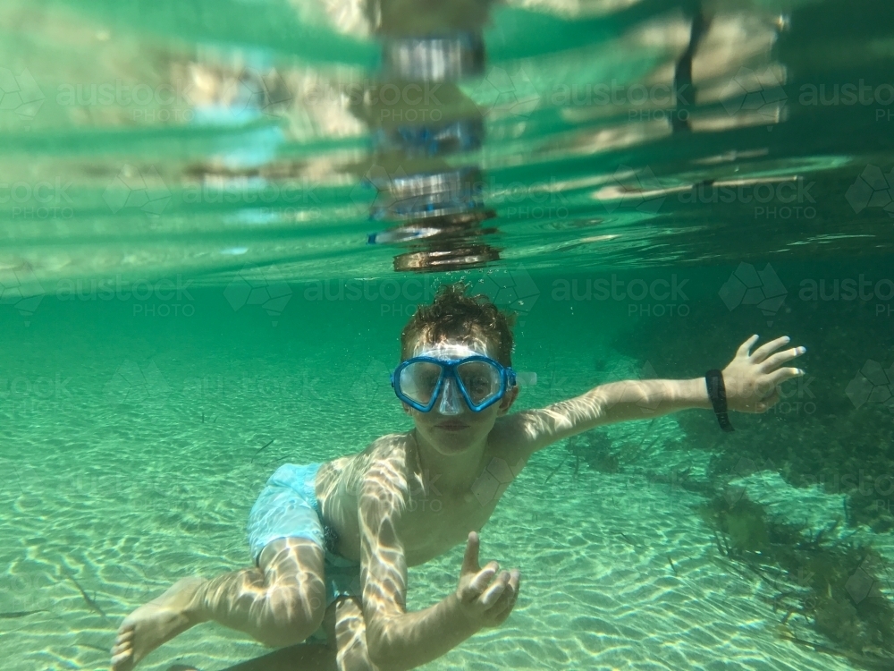 Boy underwater looking at camera wearing snorkeling mask - Australian Stock Image