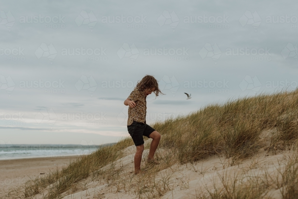 Boy walking up sand dune - Australian Stock Image