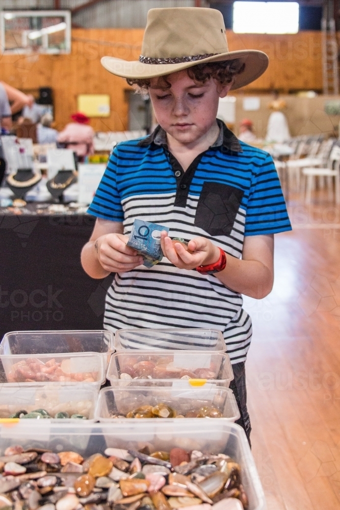 Boy wearing akubra buying stone gems holding ten dollar note - Australian Stock Image