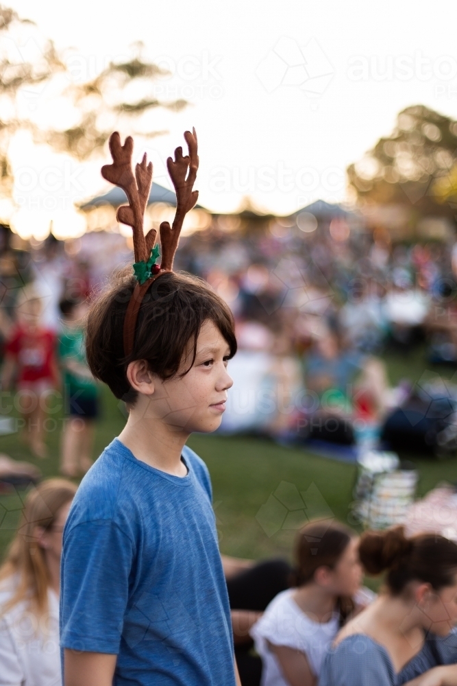 boy wearing antlers at the carols with his family - Australian Stock Image