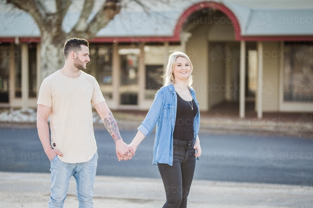 Boyfriend looking at girlfriend walking holding hands - Australian Stock Image