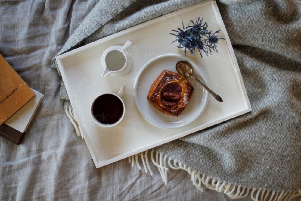 Breakfast on tray sitting on bed with books - Australian Stock Image