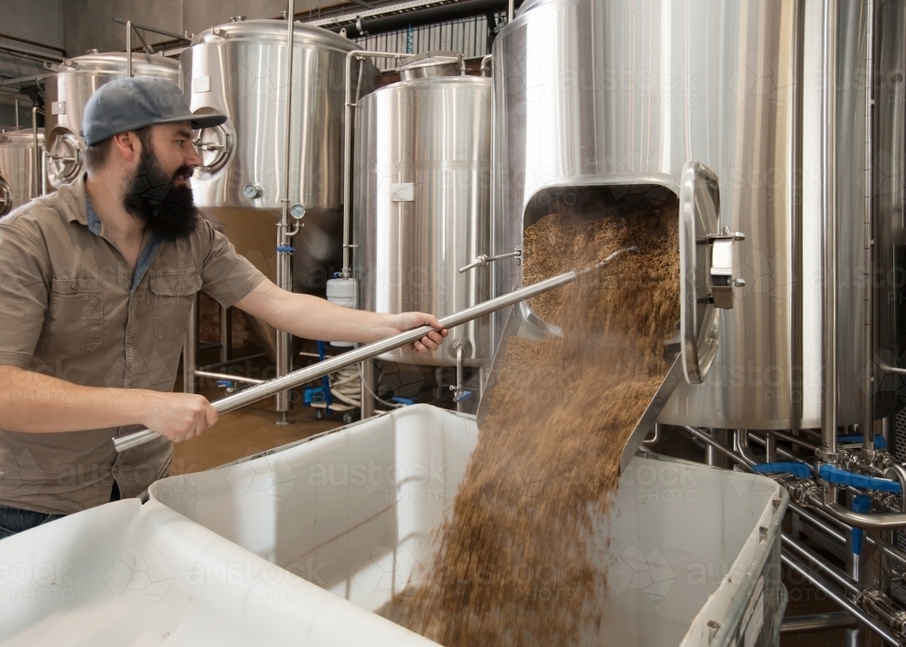 Brewer clearing out waste mash from stainless steel tank - Australian Stock Image