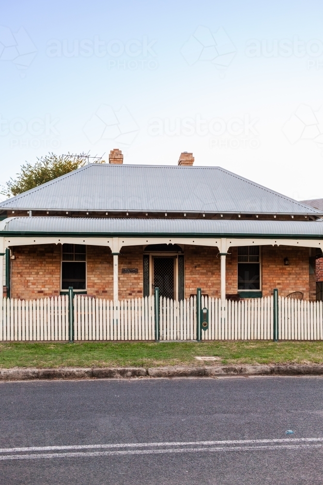 Brick house with picket fence in evening light - Australian Stock Image