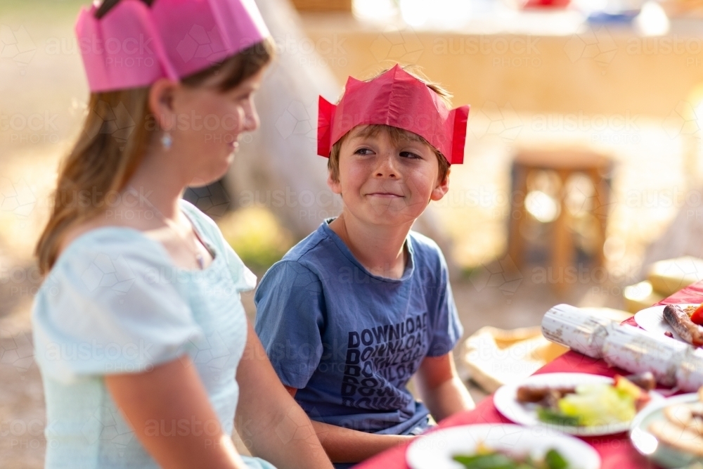 brother and sister at Christmas lunch table trying not to laugh - Australian Stock Image