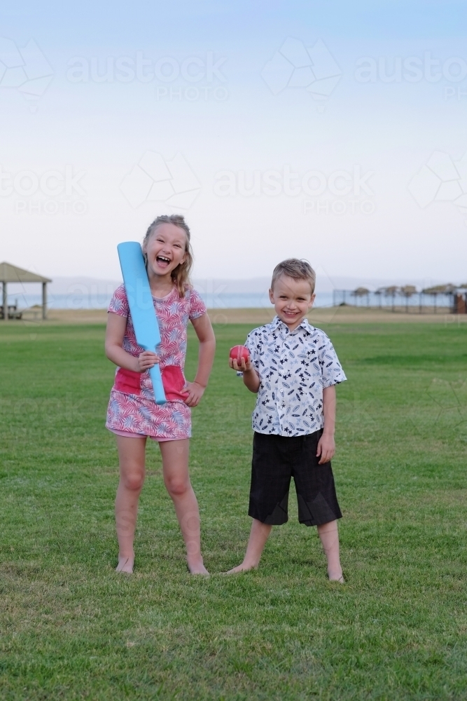 Brother and sister playing cricket in the park - Australian Stock Image