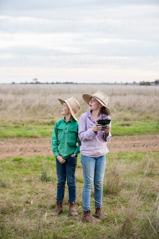 Brother and sister using a drone in the paddock - Australian Stock Image