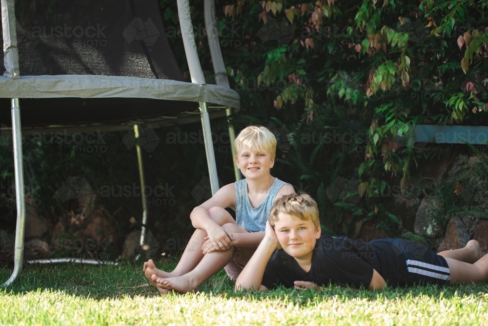 Brothers hanging out in backyard with trampoline - Australian Stock Image