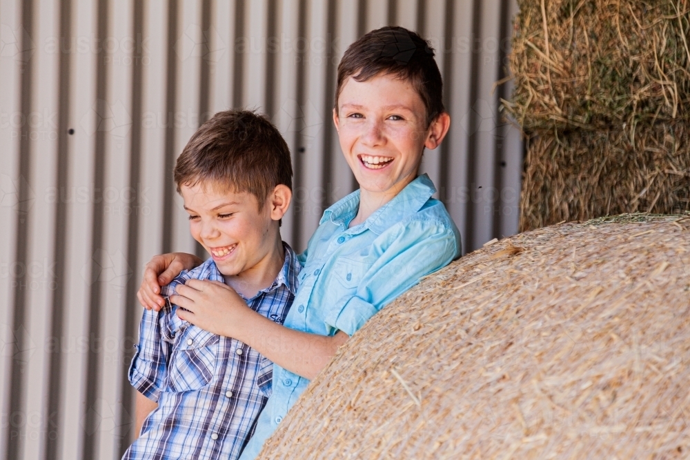 Brothers playing together in hay shed - Australian Stock Image