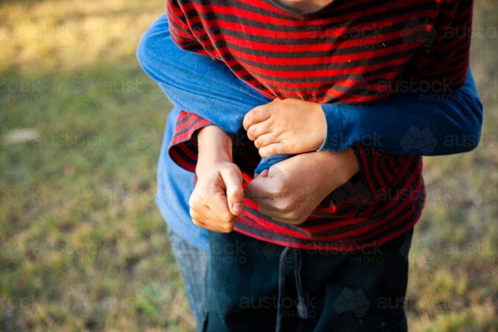 Brothers tackle wrestling each other outside - Australian Stock Image