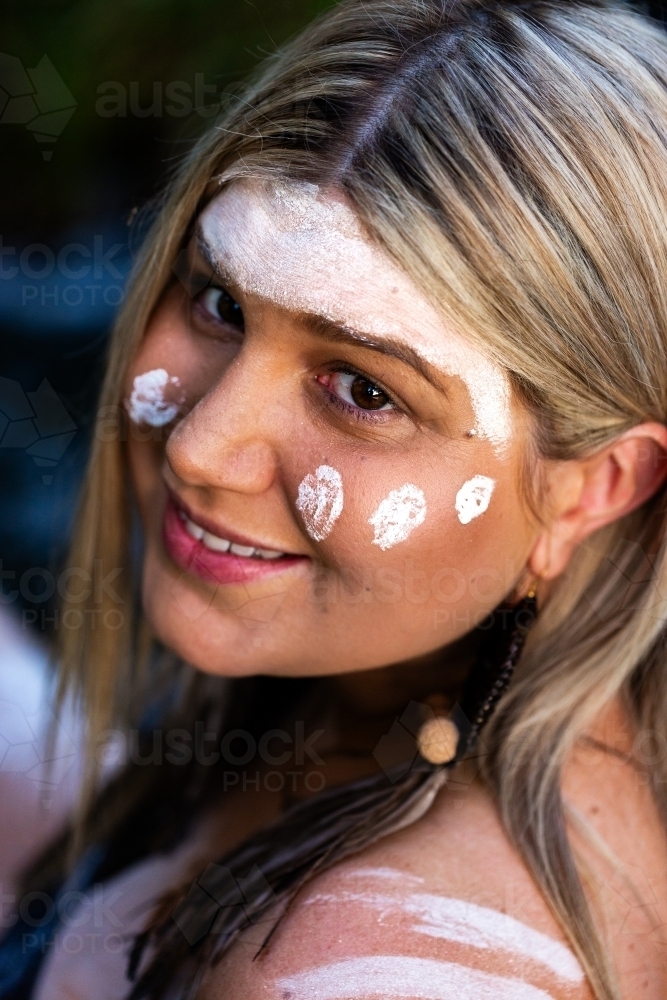 Brown eyed Aboriginal woman with traditional ochre paint on face - Australian Stock Image