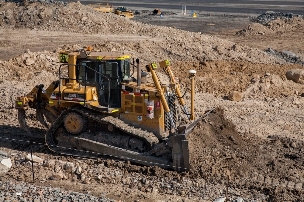 Bulldozer moving dirt beside open cut mine - Australian Stock Image