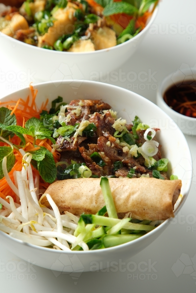 Bun Cha Gio bowls on a white countertop with a small dish of chili sauce on the side. - Australian Stock Image