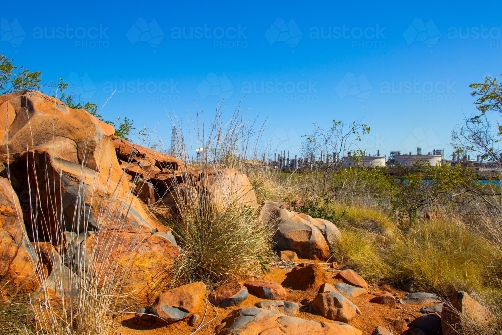 Burrup Peninsula rocky landscape with North West Shelf Gas processing plant in distance - Australian Stock Image