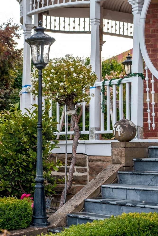 Bushes in garden with front steps up to veranda of home - Australian Stock Image