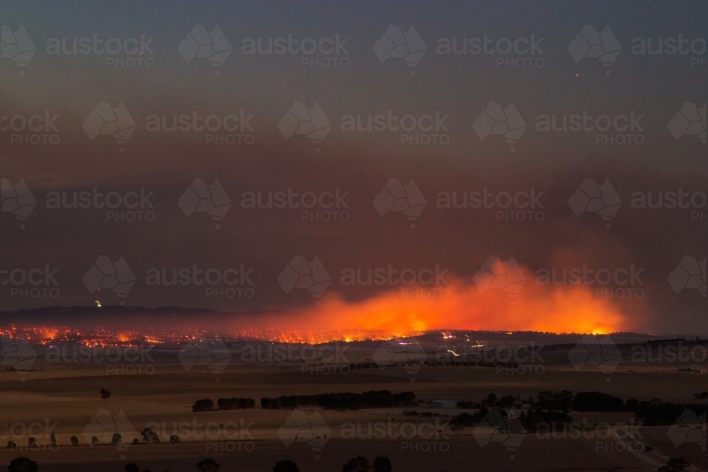 bushfire burning in rural area at dusk - Australian Stock Image