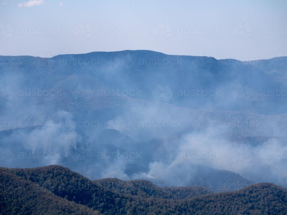 Bushfire smoke in rugged timbered country - Australian Stock Image