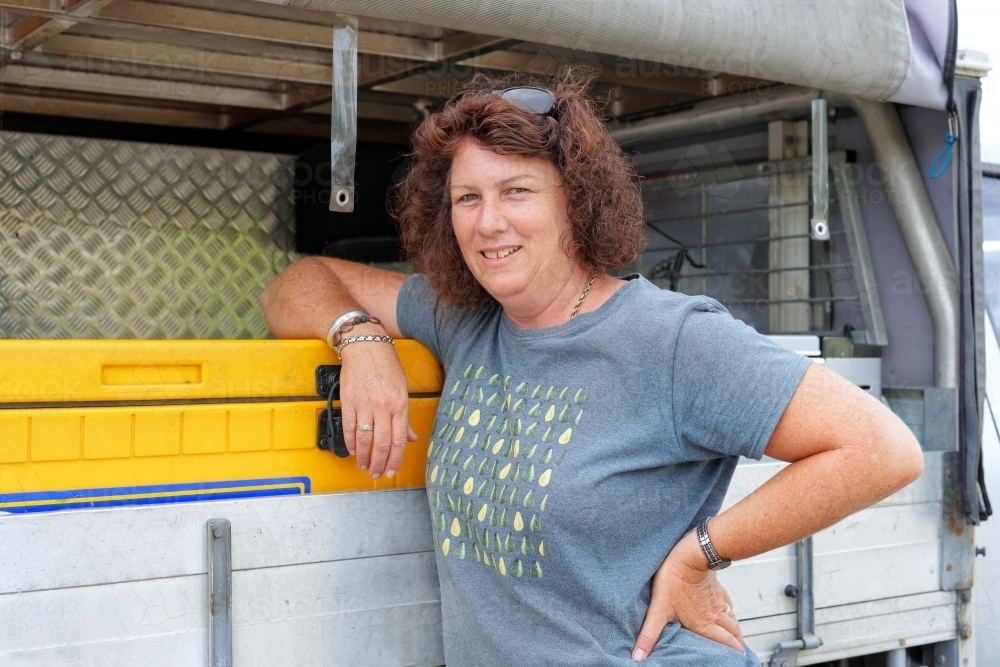 Business woman standing next to her car or ute after sales are completed - Australian Stock Image