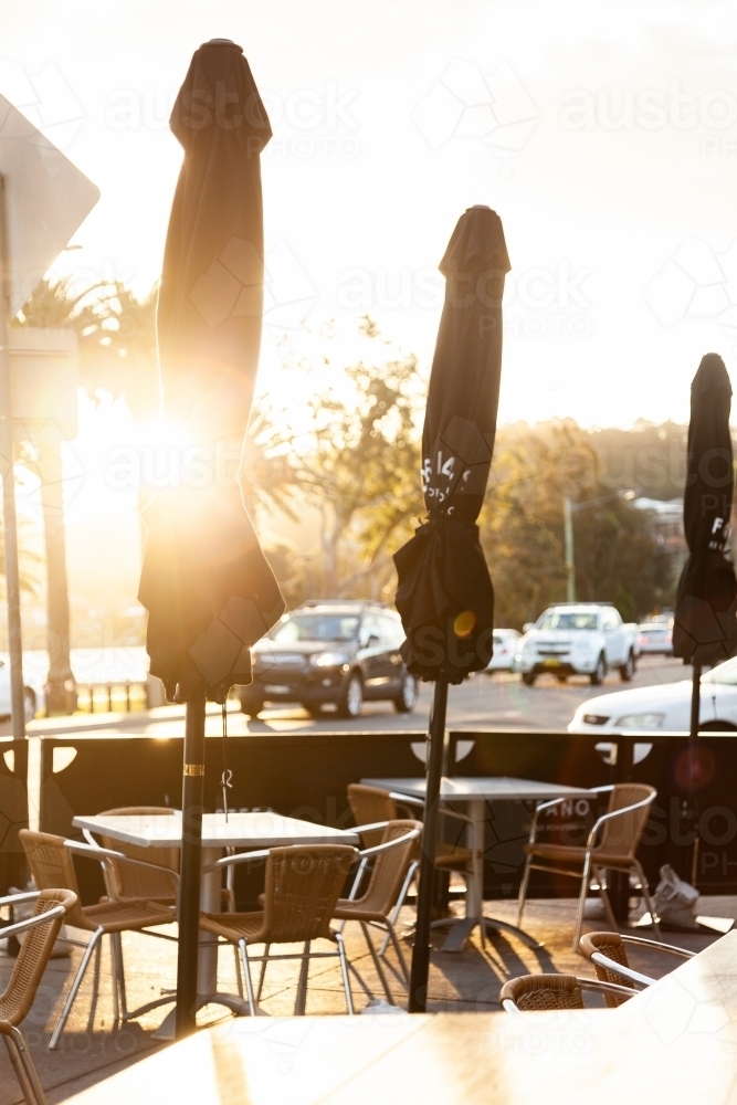 Cafe tables chairs and umbrellas on the street - Australian Stock Image