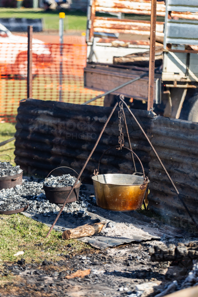 camp oven cooking damper bread on fire coals shielded by corrugated iron - Australian Stock Image